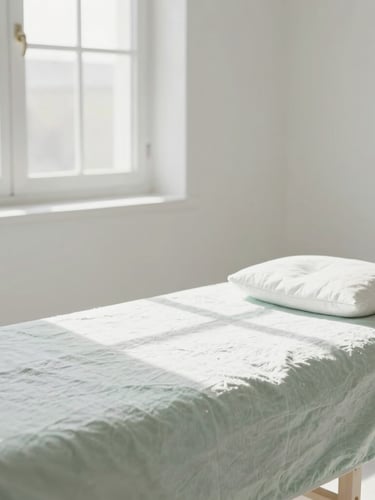 Medium shot of a sun-drenched, minimalist treatment room with soft linen textures, natural daylight streaming through a window, clean white and pale green tones, bright airy photography.