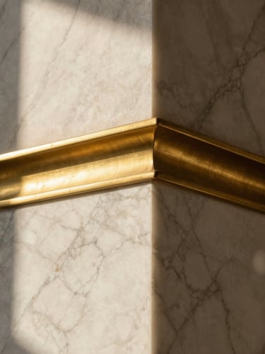 A detailed close-up of a luxury interior wall junction, showcasing veined white marble meeting brushed brass trim, dramatic low-angle golden hour lighting, architectural precision.