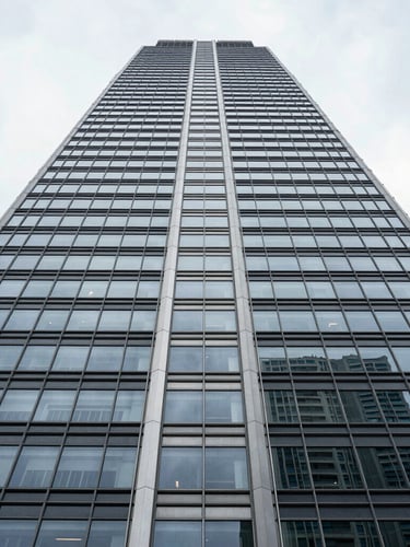 Symmetrical architectural details of a modern steel and glass skyscraper looking straight up, sharp lines, high-contrast overcast daylight.