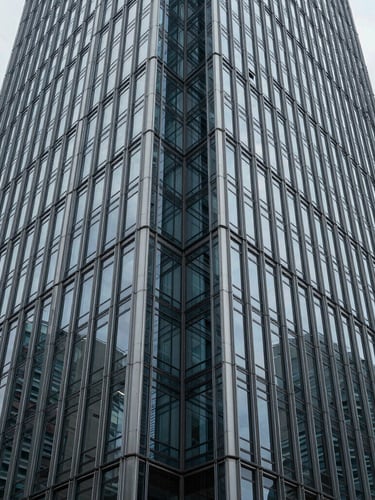 Symmetrical structural geometry of a modern glass and steel skyscraper facade, sharp linear perspective, cool overcast daylight, deep depth of field