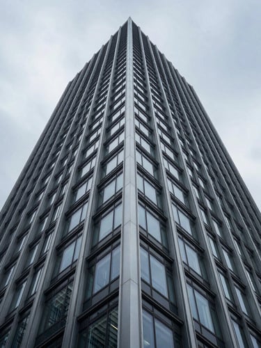 Symmetrical low-angle shot of a modern steel and glass skyscraper facade rising into a cool overcast sky, sharp linear geometry, high contrast.