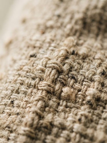 Tight macro shot of raw heavy-weight Belgian linen weave, soft afternoon window light casting gentle shadows, warm oatmeal tones, shallow depth of field.