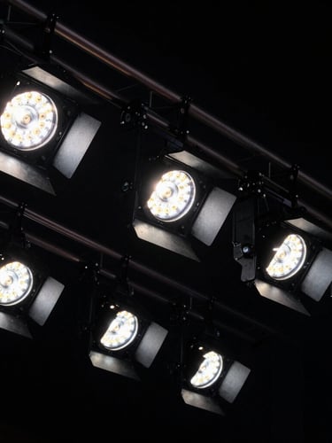 Tight macro shot of premium stage lighting details and structural rigging against a deep black background, high contrast.