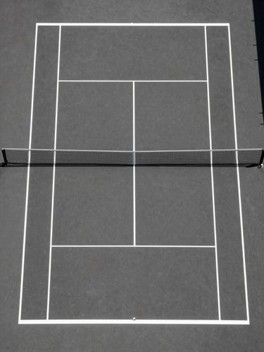 Symmetrical overhead drone shot of a pristine, empty tennis court in hard midday sun, casting sharp geometric white lines on dark asphalt charcoal.