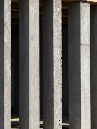 Vertical architectural framing, close-up of raw EPS monolithic panels integrated with concrete on a construction site, sharp geometry, dramatic natural light with high-contrast shadows