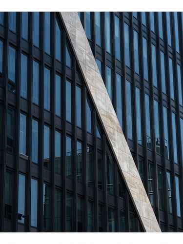 Architectural crop of a modern corporate office building facade with sharp diagonal shadows, cool high-contrast daylight, deep blue and charcoal tones, sharp focus, 35mm lens.