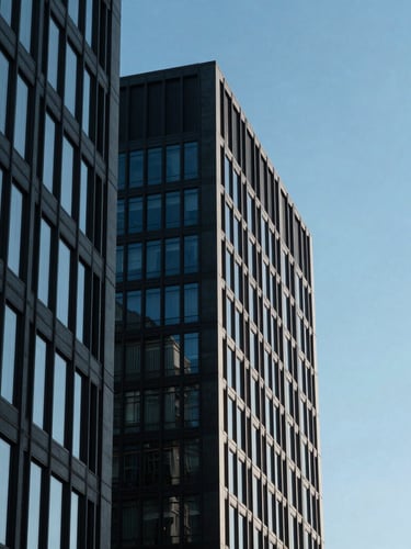 Sharp architectural lines of a modern corporate office building against a clear sky, deep blue shadows, high-contrast daylight, 35mm lens.