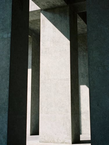 Abstract geometric composition of concrete pillars under harsh overhead light, stark contrast, desaturated cool tones, 35mm film grain.