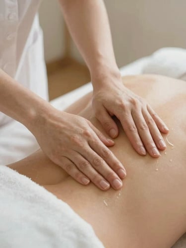 Close-up of professional therapist hands applying organic warm oil on a client back, soft lighting, clean white linen sheets, warm editorial photography