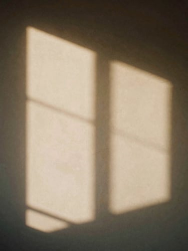 Minimalist architectural shadows on a warm plaster wall, sharp directional sunlight, contemplative quiet atmosphere, 35mm film.