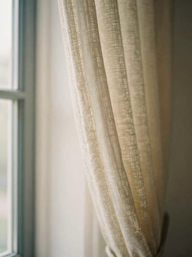 Close-up of elegant linen curtains hanging in front of a large window with soft natural sunlight streaming through, warm editorial photography, shallow depth of field, 35mm