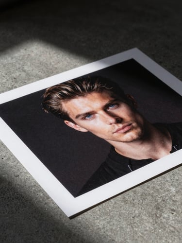Stark, extreme close-up of high-contrast printed ad layouts on a raw concrete studio floor, harsh overhead flash lighting, deep black shadows.