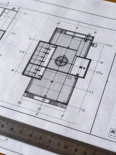 Extreme close-up of a large-format technical blueprint spread flat under daylight, showing precise dimension annotations, structural grid lines, and hand-marked measurement corrections in pencil, a steel ruler resting at the lower edge, shot from directly overhead at a slight angle, forensic and exacting, no people visible