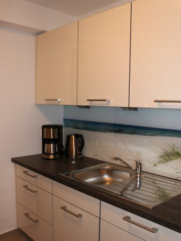 Blick auf die gegenüberliegende Küchenzeile mit der Spüle und Hängeschränke