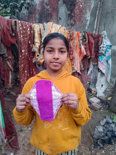 Young girl holding up a Hanaru reusable sanitary napkin