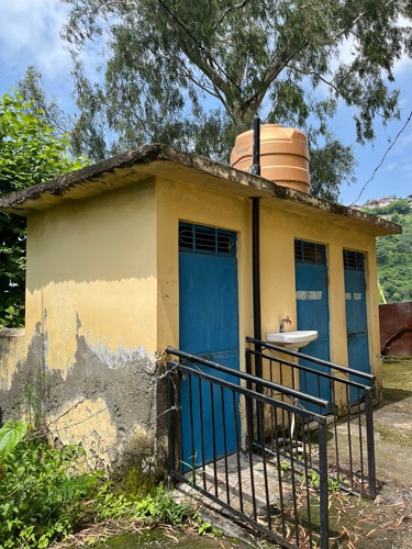 Small yellow toilet block with 3 blue doors.