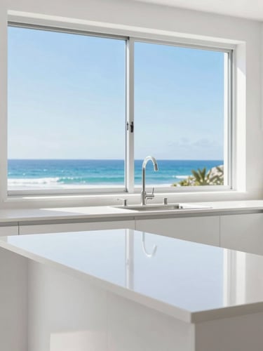 Bright high-key commercial photography of a spotless modern kitchen, sparkling white countertops, large window overlooking bright coastal Broome light, sharp focus, 35mm