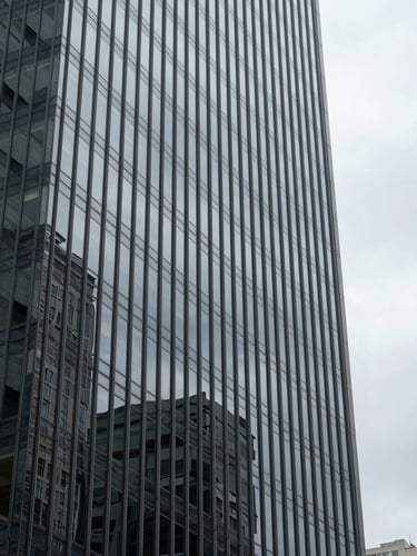 Architectural close-up of a glass-and-steel office tower facade at overcast morning, geometric reflections of grey sky, sharp vertical lines, no people, cold precision, downtown São Paulo atmosphere