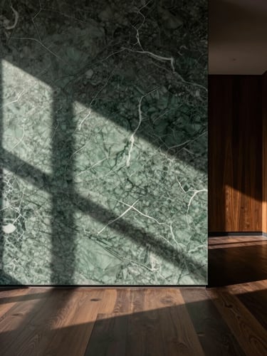 Strict one-point perspective of a minimalist interior. Low-key dramatic natural light casts long shadows across a massive veined green marble wall and dark oak millwork, emphasizing raw material textures.