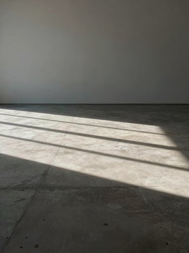 Wide empty architectural space with harsh direct sunlight casting deep geometric shadows on a concrete floor, minimalist and raw.