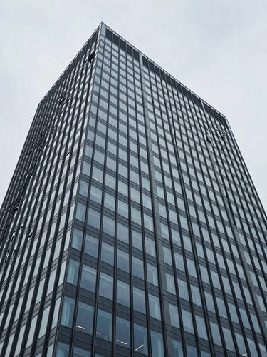 Wide-angle architectural perspective of a high-rise glass facade in Zurich, cool overcast daylight, desaturated blue and slate tones, high-contrast structural composition