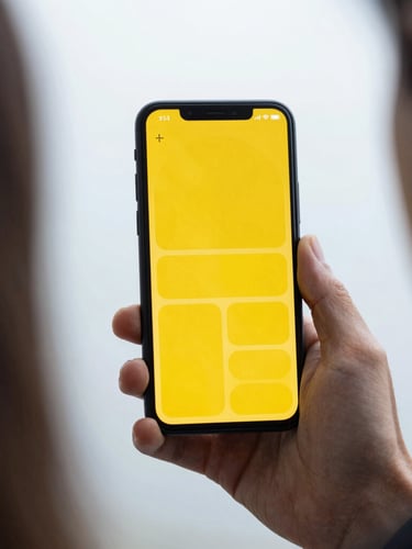 Over-the-shoulder shot of a hand holding an Android phone showing a high-contrast minimalist interface with large yellow buttons, bright overcast daylight.