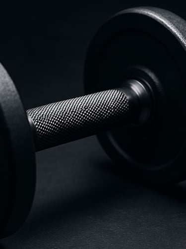 Close-up of a pristine, matte-finished steel dumbbell with precise knurling, strong directional key light carving out metallic textures, deep charcoal and safety orange accents, sharp focus, 50mm