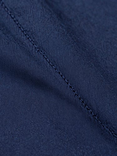 Macro extreme close-up of double-stitched seams on a heavy navy cotton garment, soft diffused studio light, crisp detail, 50mm lens
