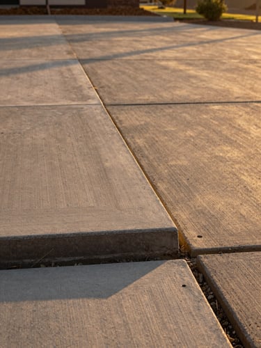 Crisp edges of a newly poured concrete driveway in Escondido, warm golden-hour sunlight highlighting the clean texture and subgrade preparation, 35mm architectural photography