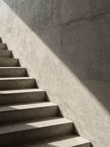 Architectural close-up of a minimalist concrete staircase with sharp shadows and warm sunlight, clean lines, high contrast, editorial photography style.