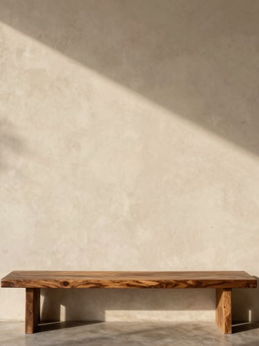 A tall portrait of a raw plaster wall meeting a dark oak bench, natural late-afternoon shadow play, warm cream tones.