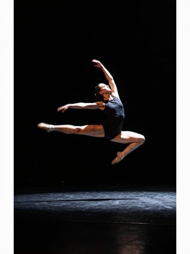 Wide stage shot from low angle, a dancer mid-leap in sharp spotlight against deep black void, full body visible, motion blur on trailing arm, high-contrast theatre lighting, left third of frame