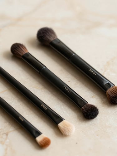 Editorial close-up of premium cosmetic tools resting on a warm cream marble surface, soft diffused natural light, shallow depth of field