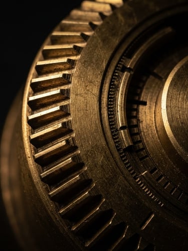 Extreme macro crop of a solid brass mechanical dial with milled teeth, side-lit with deep shadows and warm metallic highlights, 100mm lens.