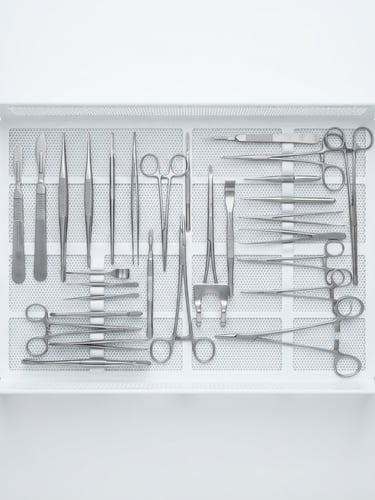 Bright high-key product photography of sterile surgical instruments arranged neatly on a white medical tray, crisp studio lighting, clinical precision, sharp focus, 85mm