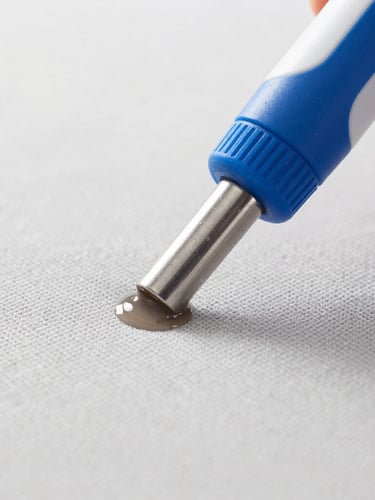 Macro close-up of a professional extraction nozzle pulling dirty water out of a light grey sofa fabric, high-key daylight, clean blue and white tones, sharp focus, professional cleaning action