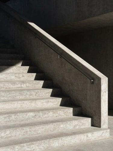 A minimalist concrete staircase ascending into shadow, sharp geometric lines, harsh afternoon sun casting deep shadows, architectural.