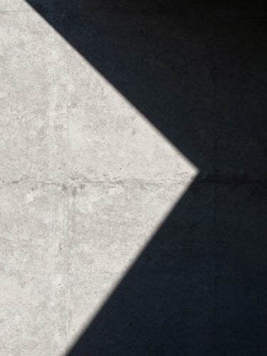 High-contrast architectural shadow cast on a raw concrete wall, sharp geometric lines, minimalist aesthetic, directional midday sun.