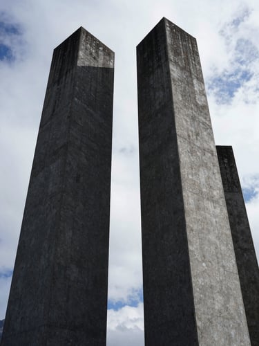 Low-angle heroic shot of monolithic architectural concrete pillars casting deep shadows under overcast alpine daylight, sharp textures, 35mm