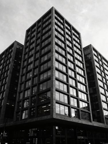 High-contrast wide-angle exterior of a modern commercial building in Albert Park, deep charcoal facade, sharp lines, reflections in glass, dramatic shadows, minimalist.