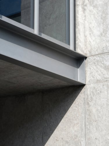 Close-up, high-contrast architectural detail of a structural steel beam connecting to a concrete wall, sharp natural daylight creating deep shadows, minimalist aesthetic, 35mm lens.