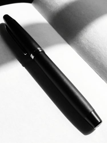 Tactile close-up of a matte black fountain pen resting on a clean white notebook, sharp architectural shadows, high-contrast black and white photography