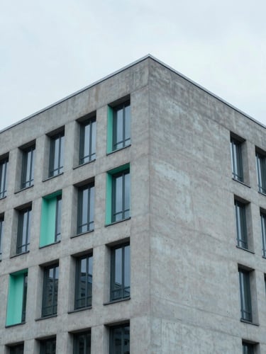 Low-angle architectural shot of a minimalist concrete office building in Berlin, cool overcast daylight, desaturated blues, sharp mint green accents, 35mm.