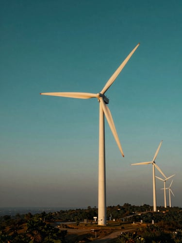 Wide environmental shot of wind turbines spinning slowly on a ridge in South India, warm golden-hour light, clean geometric lines