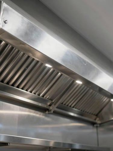 Wide angle shot of a newly installed commercial kitchen exhaust hood system in a Doha restaurant, clean stainless steel surfaces reflecting cool-toned overhead lights, 50mm.