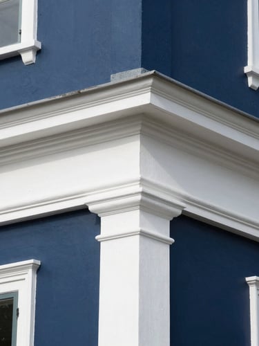 Close-up architectural detail shot of crisp white trim lines against deep navy exterior paint on a historic home, bright natural daylight, sharp focus.