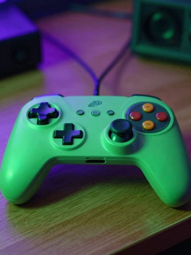 A close-up of a retro game controller resting on a wooden desk illuminated by toxic green and electric purple neon ambient light, 35mm lens