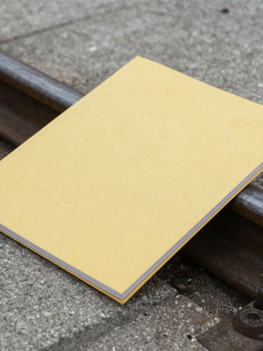 Close-up of a high-quality technical documentation folder resting on a concrete rail platform, overcast daylight, desaturated steel tones, 35mm