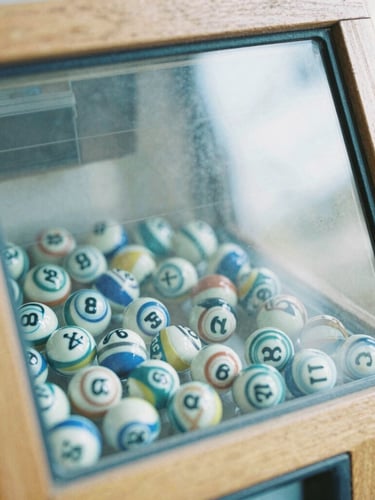 Close-up detail of a physical lottery draw machine with transparent glass and numbered spheres, soft natural overcast light, 35mm