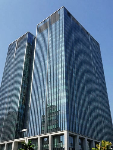 Modern architectural office building in Jakarta with clean glass facade reflecting bright blue sky, wide environmental shot, editorial photography